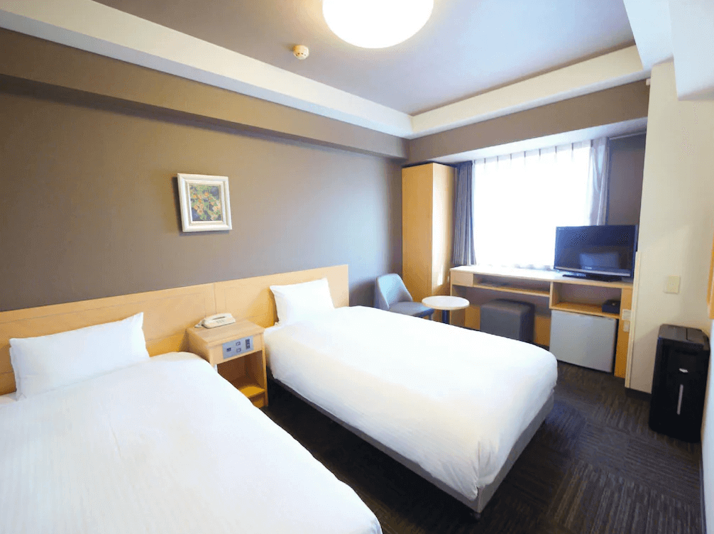 【函館住宿】露櫻GRANTIA函館站前店雙床房，簡約設計搭配木質傢俱，窗邊設有電視與小桌椅，空間舒適明亮。