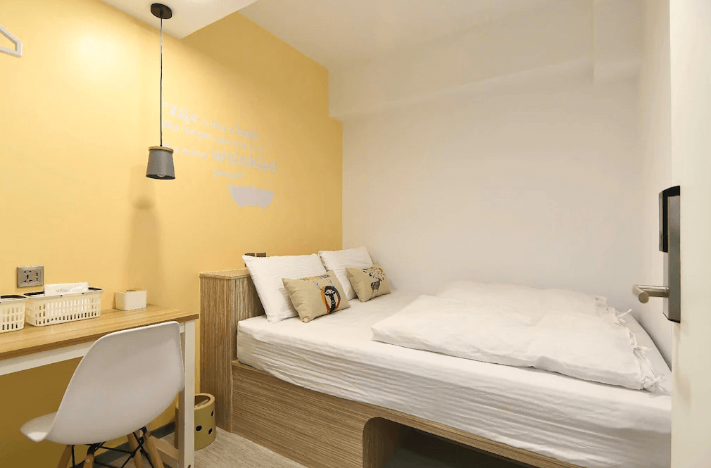 【三多商圈住宿】飛行家青年旅館 FLYINN HOSTEL 單人房，設有黃色與白色搭配的溫馨空間，內含雙人床、書桌與吊燈，簡約舒適。