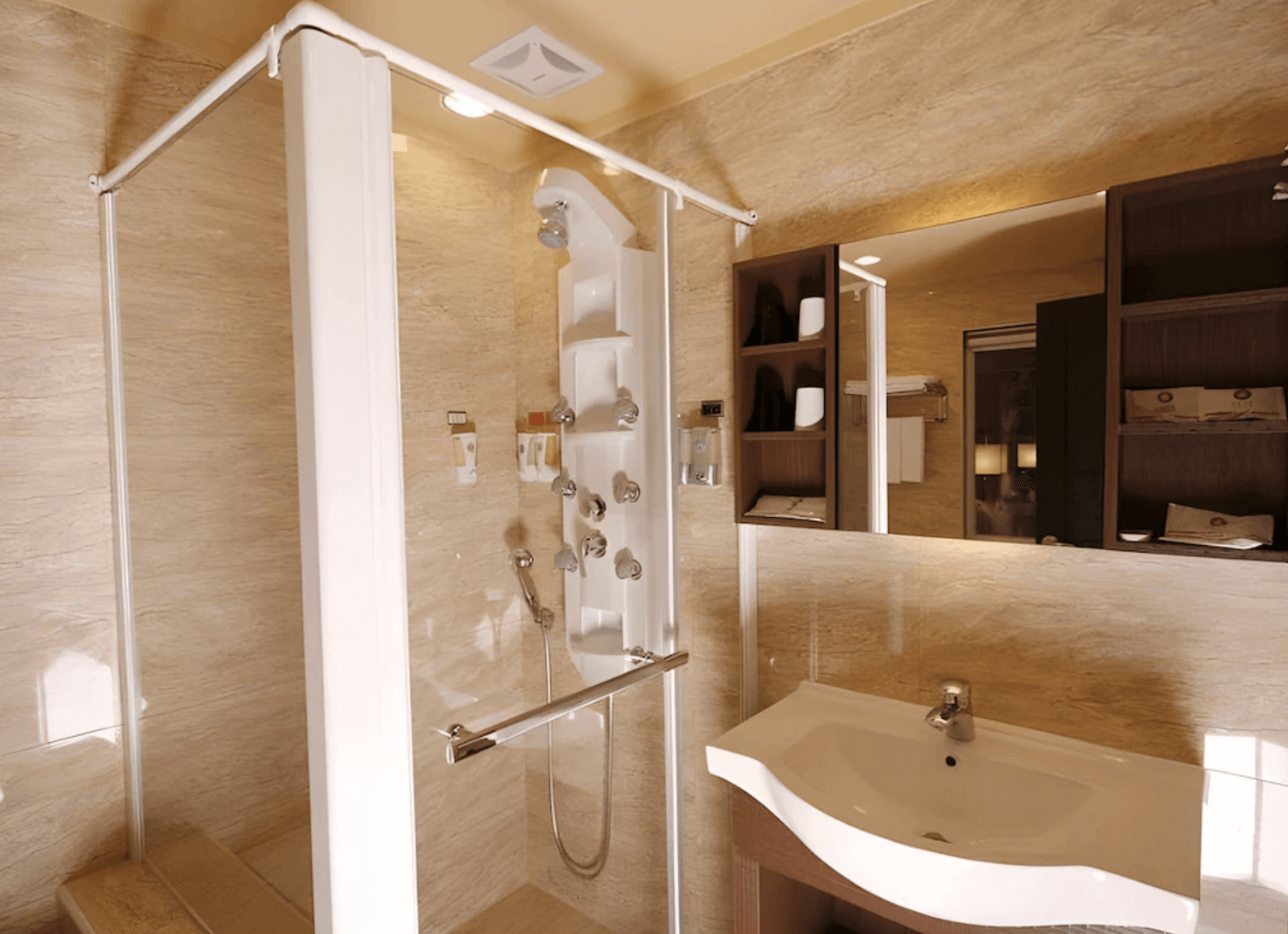 【前金住宿】高雄都會商旅 M-Hotel 浴室，設有淋浴間、洗手台與大面鏡子，整體以米色大理石紋設計，乾淨典雅。