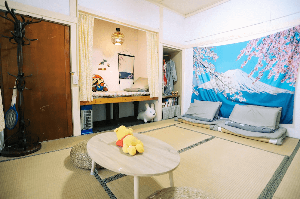 【鳳山住宿】鳳山79背包客黃埔青旅 和風榻榻米房日式榻榻米房型，牆上掛有富士山與櫻花掛布，床位小巧溫馨，房間內有可愛玩偶裝飾，氛圍輕鬆溫暖。