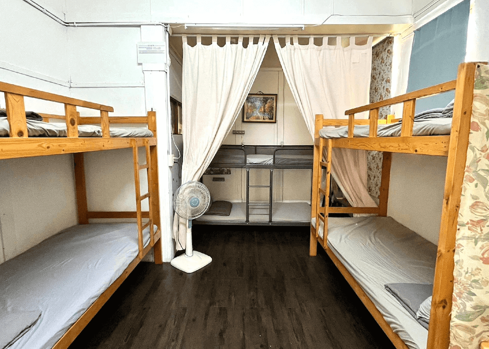 【鳳山住宿】鳳山79背包客黃埔青旅 多人上下舖房整潔的多人宿舍房間，木質上下舖床位整齊排列，中間設有白色布簾隔間，簡單舒適，適合背包客入住。