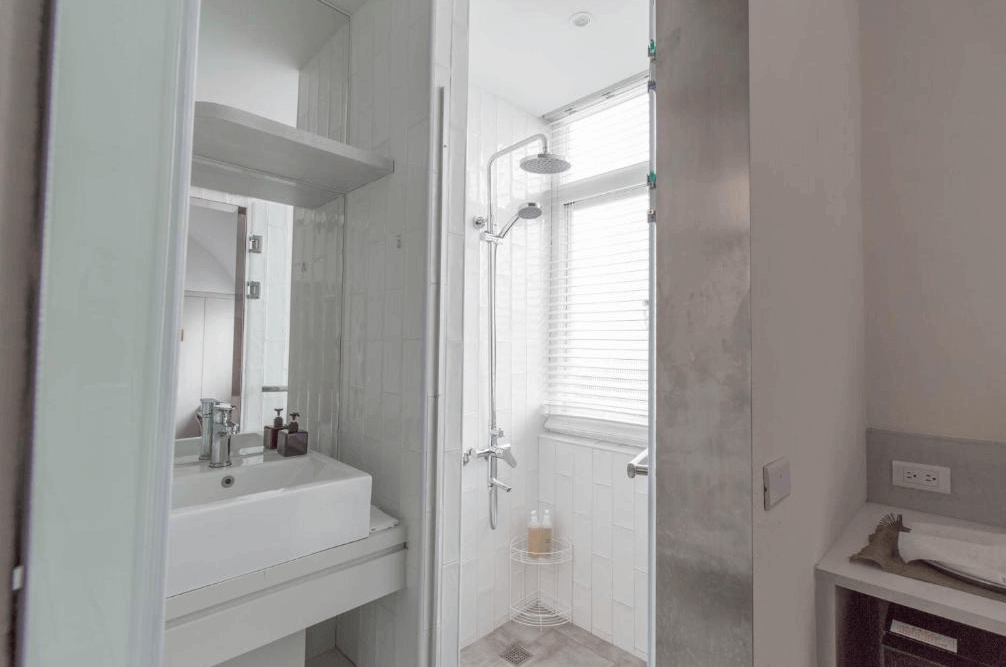 【高雄中央公園住宿】鶴宮寓浴室：乾濕分離的明亮衛浴空間，設有雨淋花灑與簡約洗手台，白色磚牆清爽潔淨。