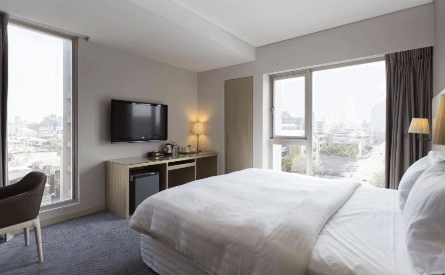 【前金住宿】麗馨精品商旅七賢館 — 現代簡約的客房設計，雙人大床搭配木質元素，窗邊可欣賞高雄市景。