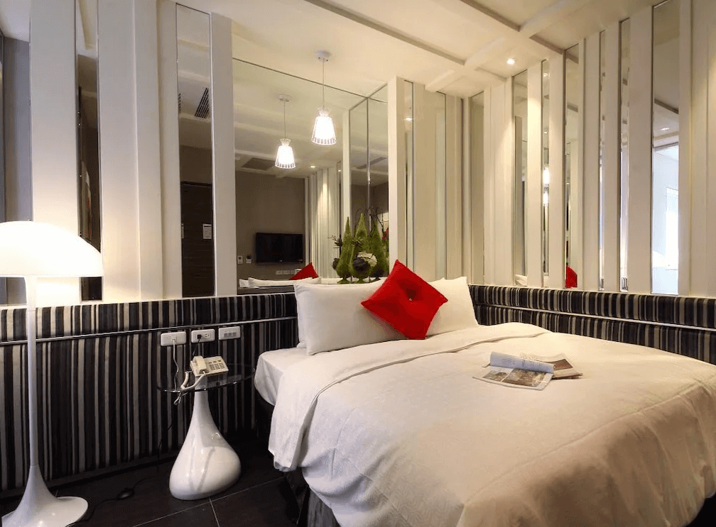 【鳳山住宿】麗馨精品商旅鳳山館 雙人房設計感十足的雙人房，床邊以鏡面與直條線條裝飾，黑白條紋牆面搭配紅色抱枕點綴，簡約時尚。