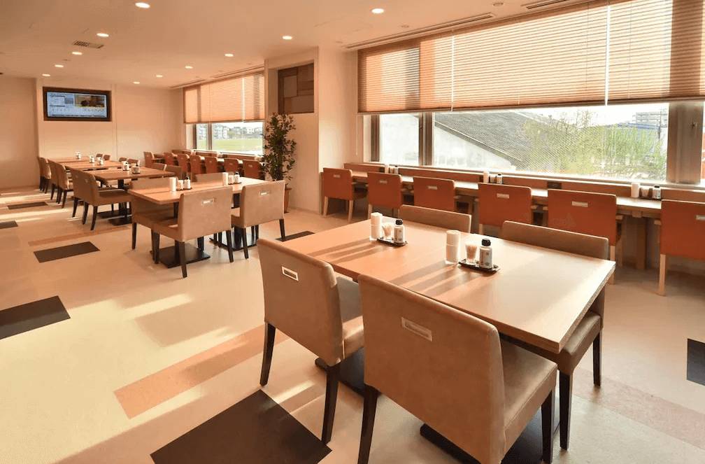 【網走住宿】「Dormy Inn 網走天然溫泉飯店」的餐廳環境，採用大片窗景與柔和自然光，木質桌椅排列整齊，提供明亮舒適的用餐空間。