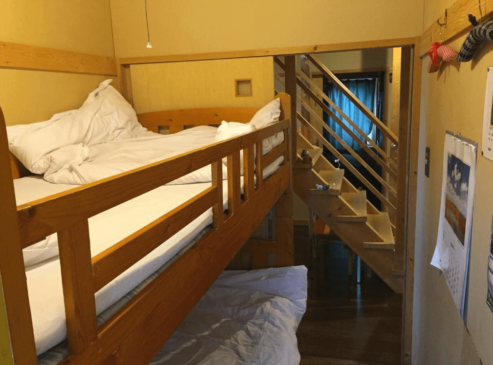 【網走住宿】「Imodango村民宿」的上下鋪房型，木質結構溫暖自然，房內以簡約設計搭配樓梯通往二樓空間，營造溫馨且具有家庭感的住宿氛圍。