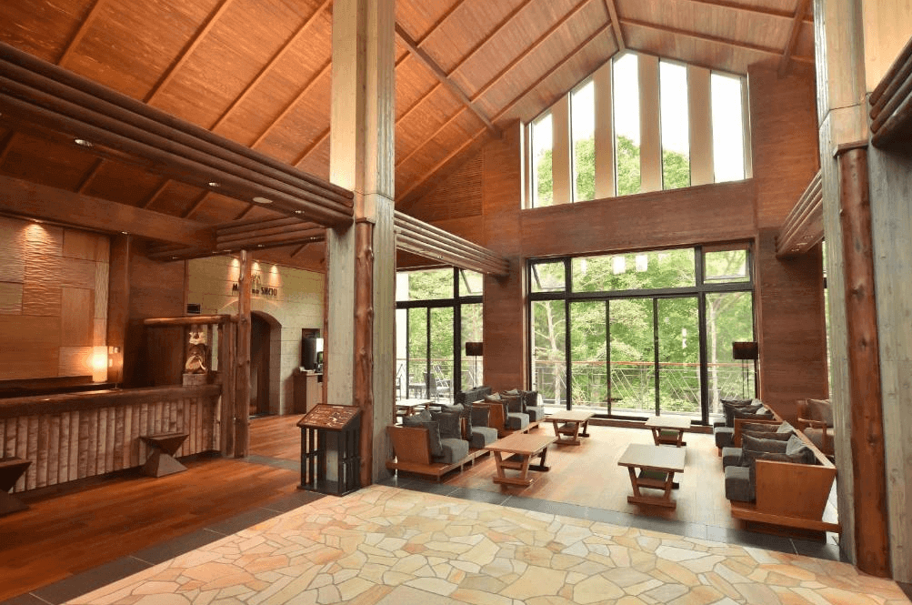 【釧路住宿】La Vista阿寒川飯店大廳，挑高木造屋頂搭配大片落地窗，採光明亮可眺望森林景觀，展現自然系渡假風格。