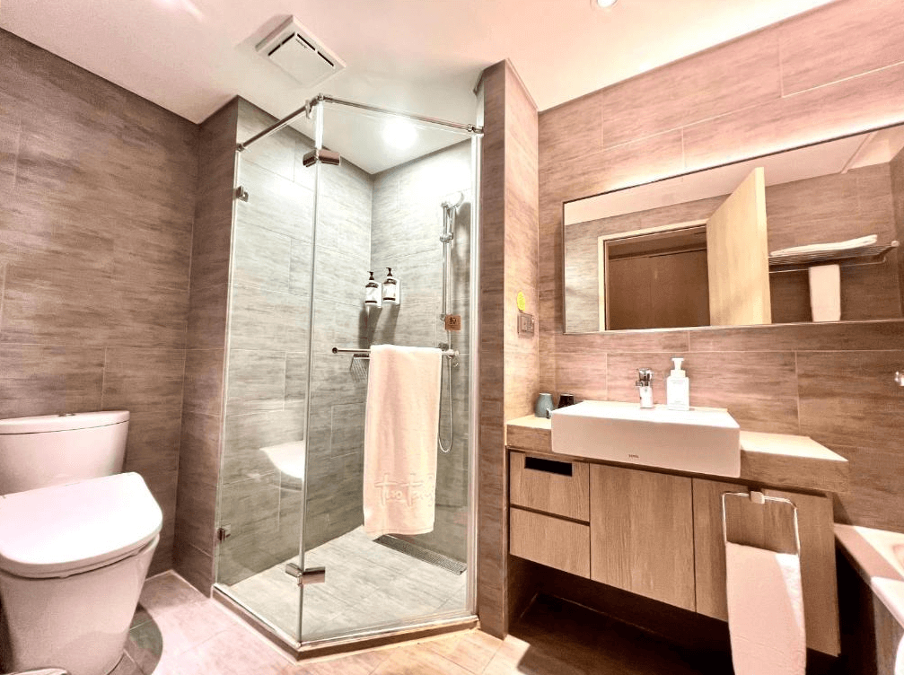 【三重住宿】Two Tails Hotel 浴室空間，採用乾濕分離設計，木質調牆面與明亮照明，配有獨立淋浴間、洗手台與TOTO馬桶，乾淨舒適。