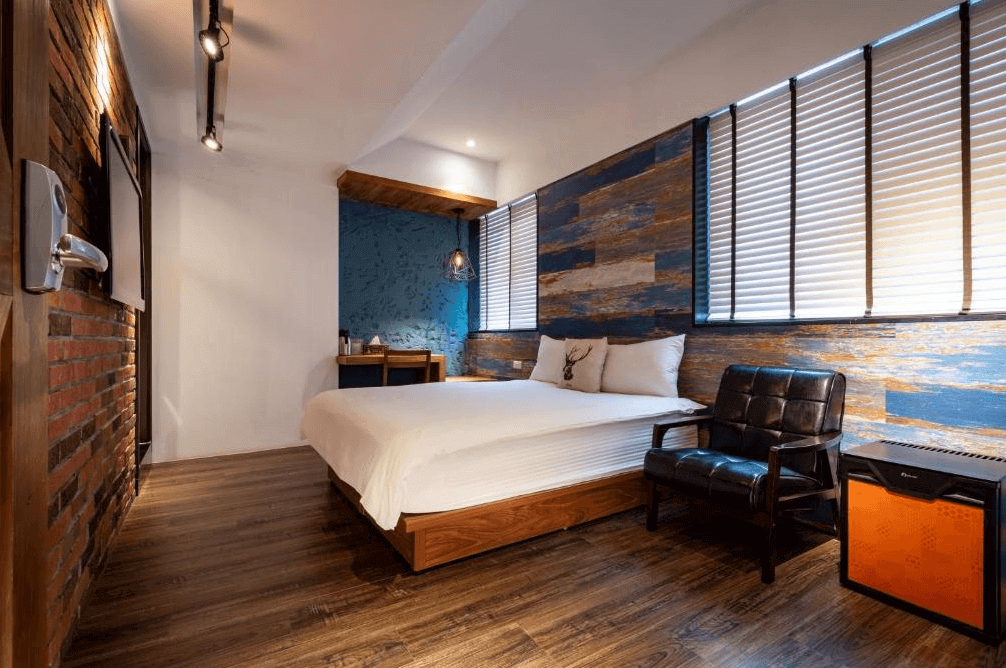 【瑞芳住宿】九份不厭晴民宿｜工業風雙人房設計，結合木質與磚牆元素，配有皮革沙發與藍色特色牆面，展現質感與溫度兼具的住宿空間。