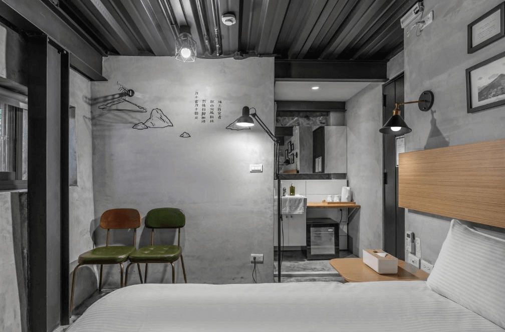 【瑞芳住宿】九份山經｜工業風雙人房，以灰色水泥牆與黑色金屬結構打造極簡氛圍，牆面上有詩句與藝術掛畫，展現文青風格的住宿空間。