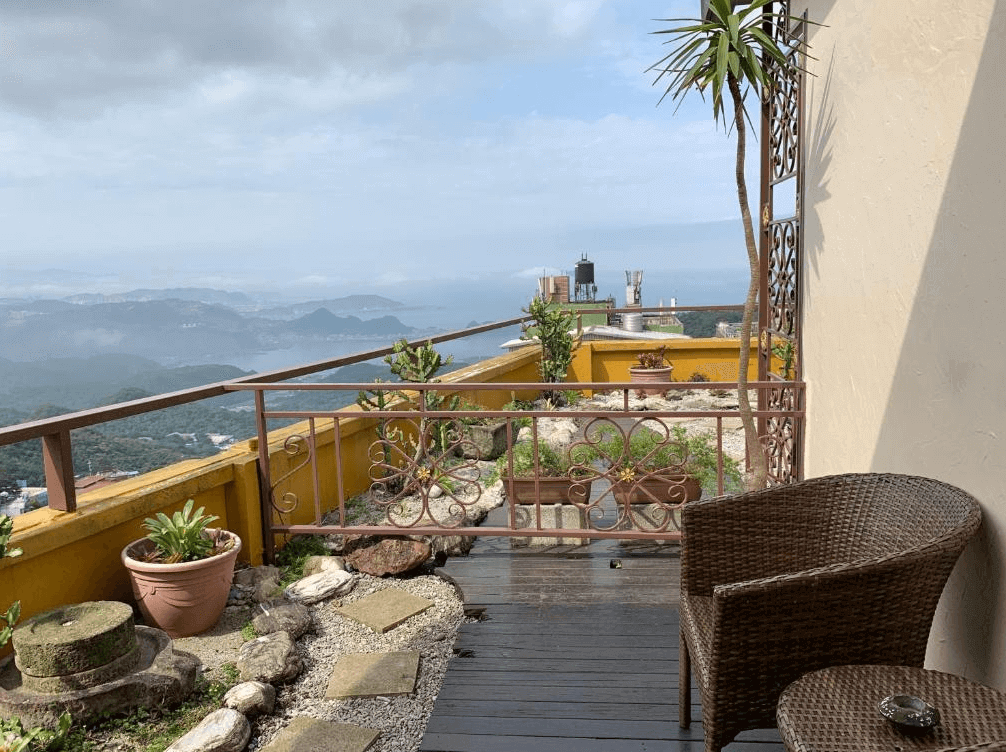 【瑞芳住宿】九重町客棧｜露天陽台景觀區，可遠眺山海連天景致與九份山城，木質步道與藤椅設計，打造愜意放鬆的度假空間。