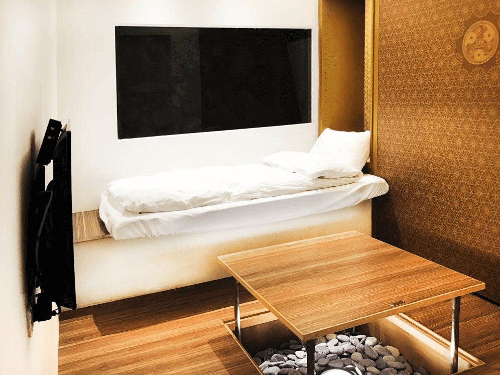 【瑞芳住宿】井上天花｜日式榻榻米風格單人房，房內設有木質升降桌與小石裝飾，牆面以金色花紋點綴，空間典雅富禪意。