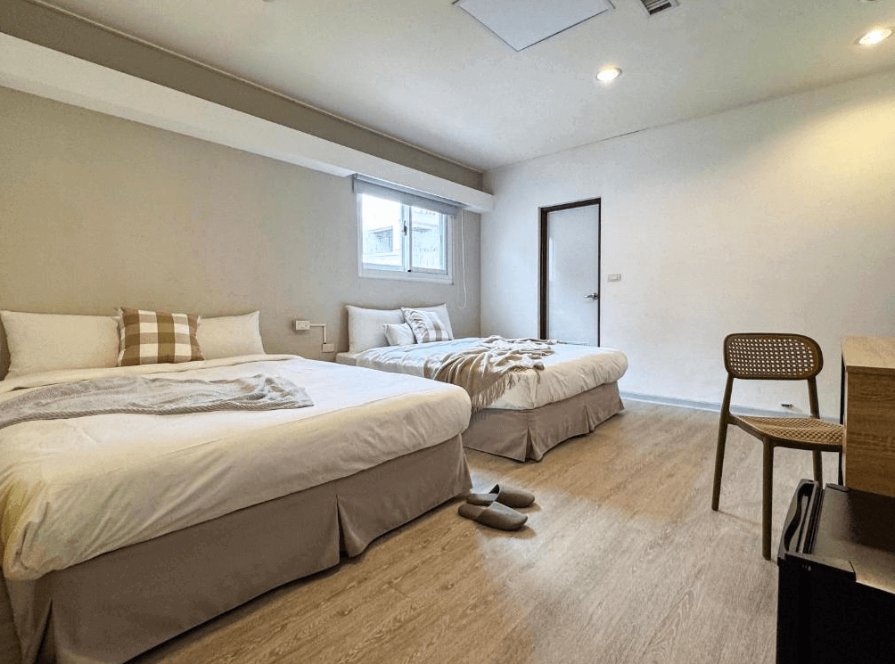 【台南寵物友善住宿】信然文旅・首學的四人房，房內設有兩張大床與木質地板，整體以簡約米灰色調打造溫馨氛圍，採光柔和，空間寬敞舒適。