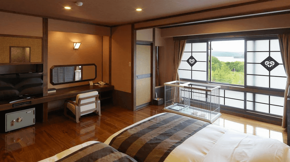 【網走住宿】「北天之丘網走湖鶴雅度假村」的湖景雙床房，設有大片窗景可遠眺網走湖，木質地板與和風拉門設計，房內附寵物籠，寵物旅客也能安心入住。