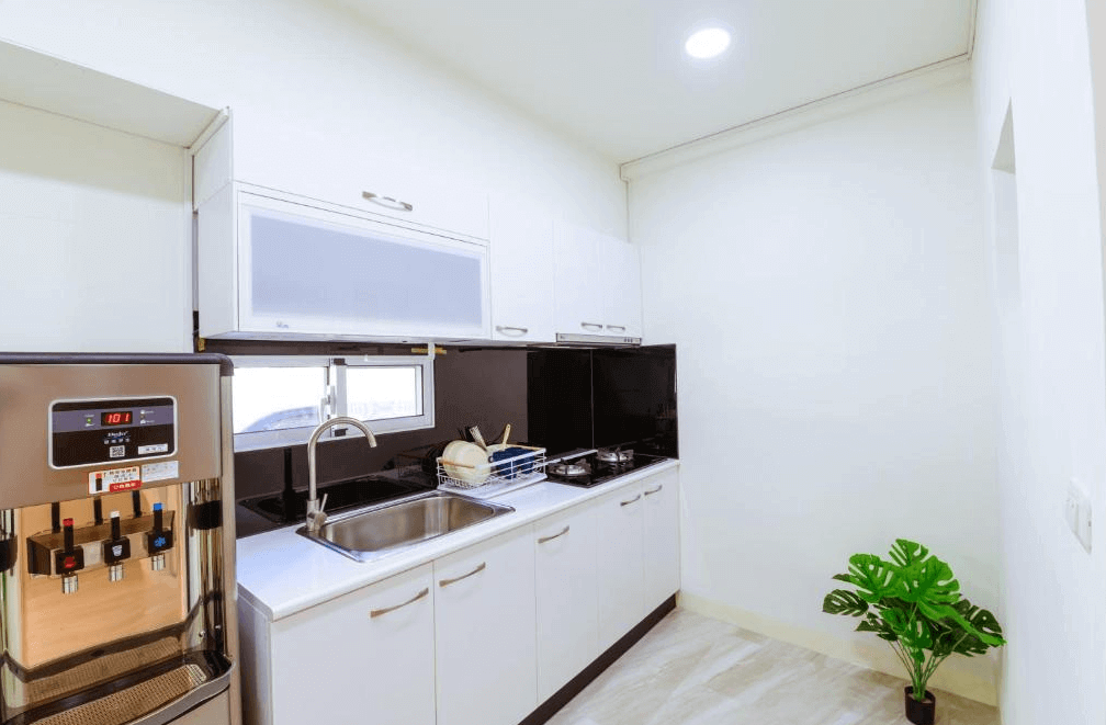【台南寵物友善住宿】台南梨泰院民宿的廚房區域，設有不鏽鋼飲水機、雙口瓦斯爐與白色收納櫥櫃，乾淨整潔且設備齊全，適合旅客自行烹調。
