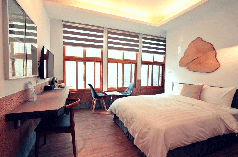 【台南寵物友善住宿】台南民宿湧福驛站的海景雙人房，採光良好、大片木框窗搭配溫潤木質地板與自然風格裝飾，牆面有原木切片藝術擺飾，整體空間兼具質感與放鬆氛圍。