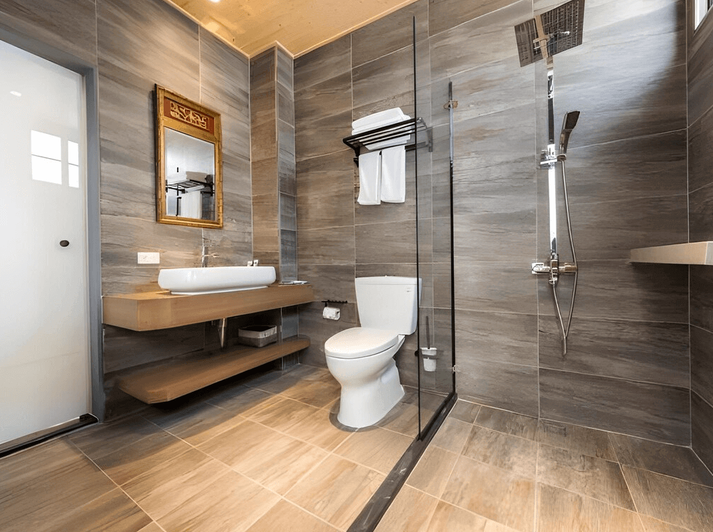 【台南寵物友善住宿】台南民宿湧福驛站的衛浴空間，採用現代灰階磁磚設計，乾濕分離淋浴間搭配木質洗手檯與大型鏡面，整體乾淨明亮且充滿設計感。