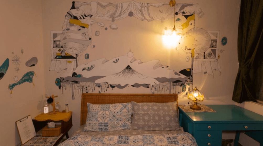 【台南寵物友善住宿】太陽慢慢走 Red Letter Day 雙人房，牆上以藝術插畫風格描繪山景與人物，搭配復古燈飾與藍色書桌，營造文青懷舊的住宿氛圍。