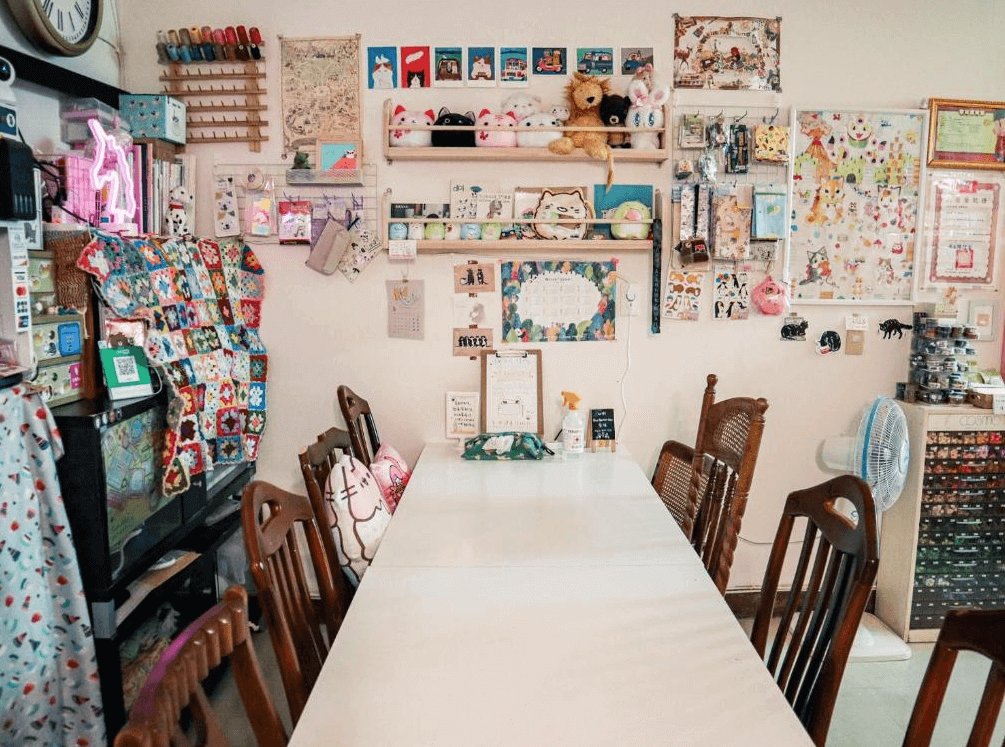 【台南寵物友善住宿】太陽慢慢走 Red Letter Day 民宿的手作教室空間，牆上佈滿插畫與裝飾，搭配長桌與木椅，適合舉辦文具交流或DIY手作活動。