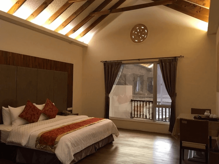 【六龜住宿】高雄六龜【寶來山澤居 Villa 渡假小木屋】溫馨套房，挑高木樑天花設計，大片落地窗採光良好，配有雙人床與典雅紅金床巾，展現自然與溫泉度假氛圍。