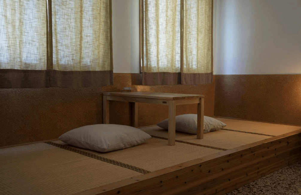 【台南寵物友善住宿】巷弄 x 台南民宿榻榻米空間，設有木桌與坐墊，窗邊自然光灑落，營造靜謐悠閒的茶席氛圍，展現簡約日式美學。