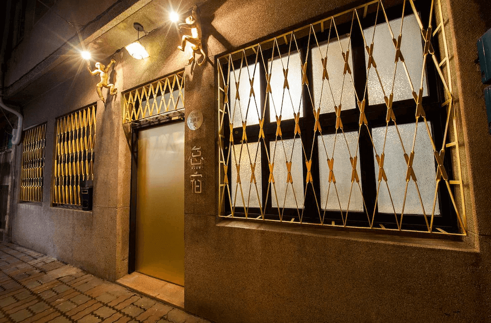 【台南寵物友善住宿】怠宿 SLOW 建築外觀，復古灰牆搭配金色鐵窗設計，夜間燈光溫暖柔和，展現懷舊又摩登的老屋魅力。