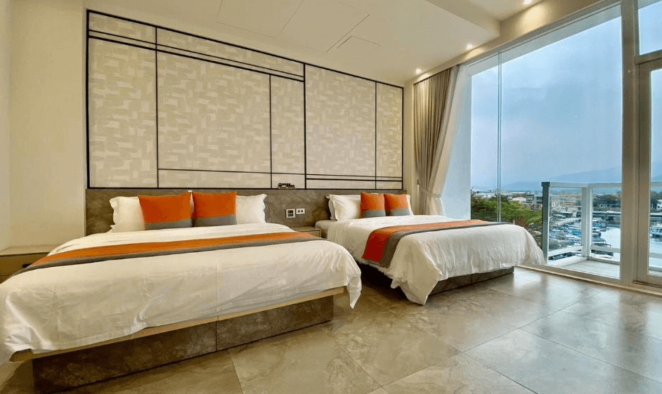 【枋寮住宿】「愛琴海岸海景精品民宿的雙床海景房，房內設有兩張大床，採光明亮，大片落地窗可眺望港灣景色，裝潢現代簡約、配色橘灰相間。」