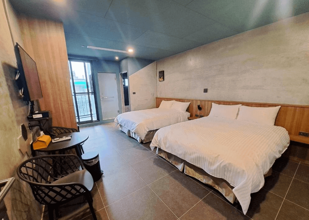【枋寮住宿】「春枋旅居 四人房，兩張大床搭配簡約木質牆面與灰藍色調設計，房內設有電視、小桌椅與陽台，空間寬敞舒適。」