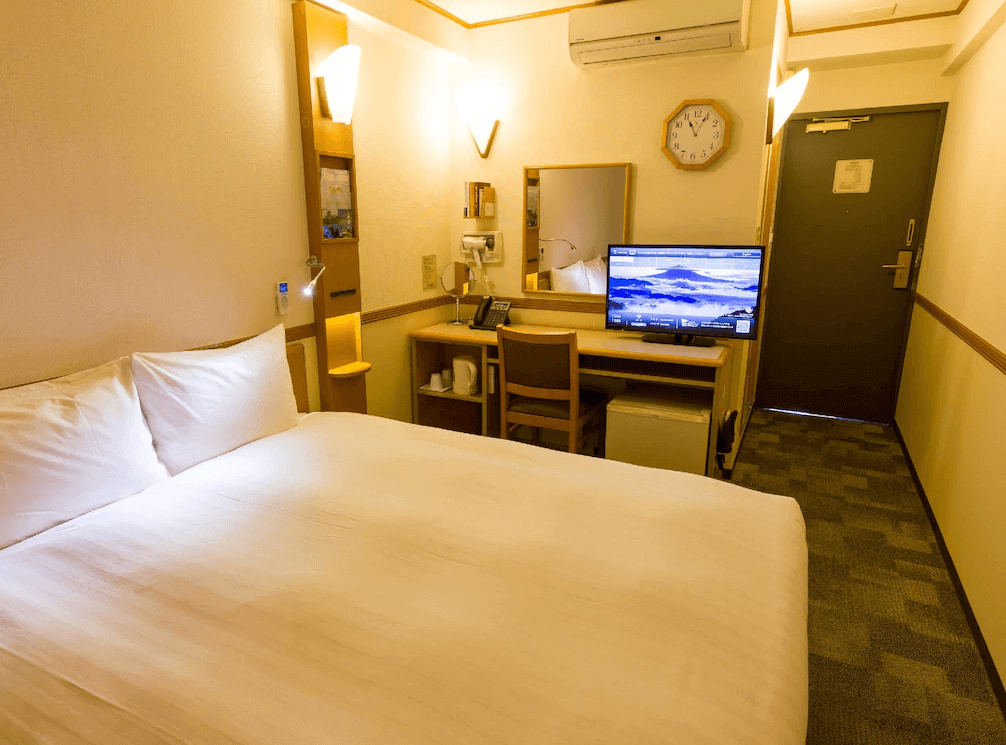 【網走住宿】「東橫INN北海道鄂霍次克網走站前」的單人房，設有一張大床與書桌區，內裝簡約溫馨，附有電視、鏡台與閱讀燈，適合商務旅客入住。