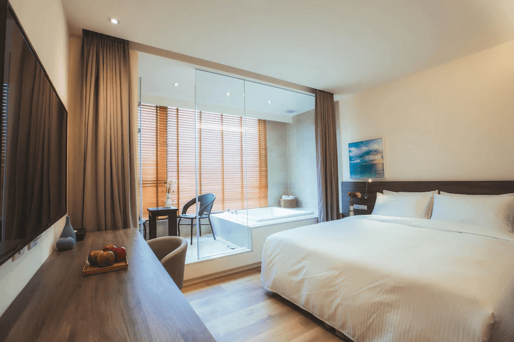 【枋寮住宿】「枋客文旅 FangLiao Hotel 精緻雙人房，房內設有舒適大床與木質桌椅，玻璃隔間外為半開放泡湯浴池空間，採光明亮、氛圍溫馨。」