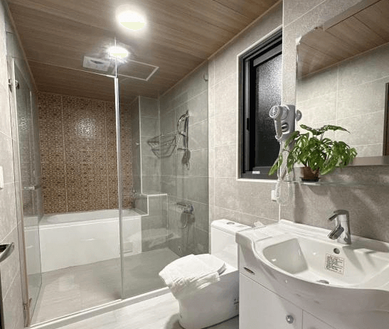 【枋寮住宿】「枋寮18遛遛居 浴室空間，設有浴缸、乾濕分離淋浴區與白色洗手台，牆面採灰色磁磚與木質天花板，整潔明亮。」