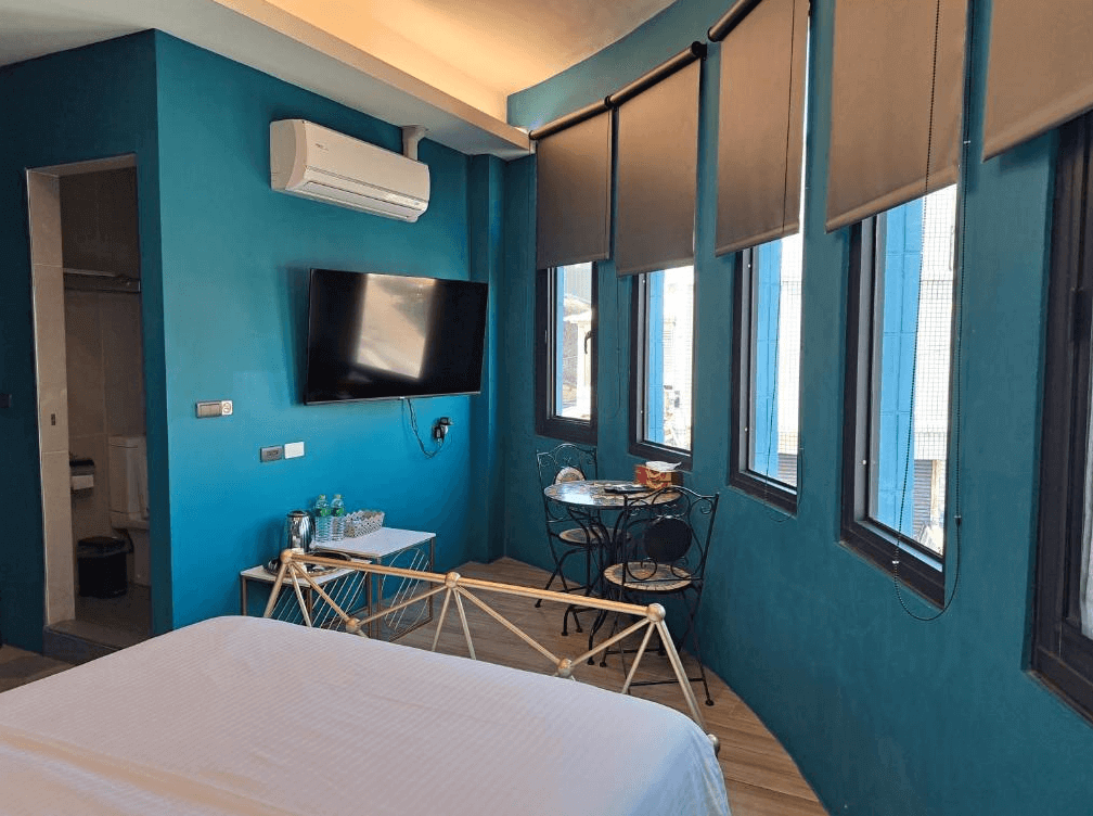 【枋寮住宿】「枋寮春來輕旅 雙人房，大片窗戶採光充足，設有電視與小圓桌，空間寬敞明亮，呈現簡約藍色系風格。」