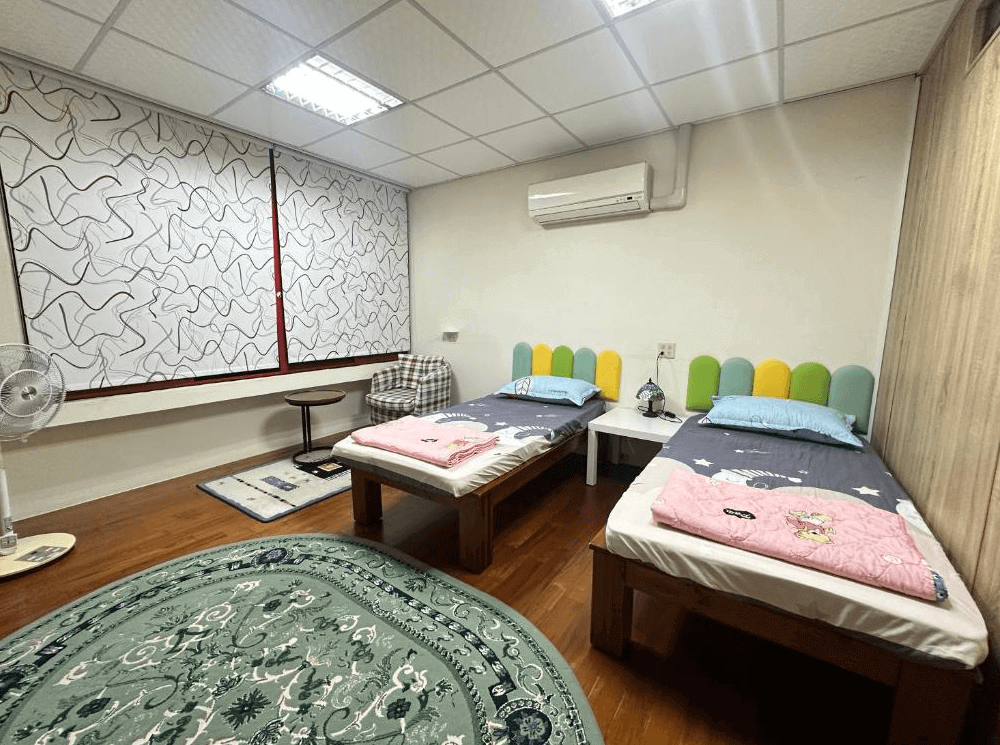 【枋寮住宿】「枋寮枋居背包客棧 兩床房型，木質地板與繽紛床頭設計，簡約溫馨風格，房內設有冷氣、座椅與閱讀燈，適合旅人休息。」