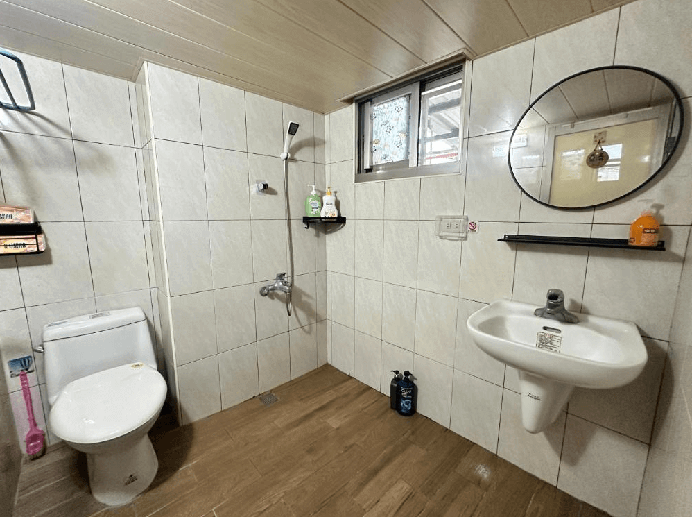 【枋寮住宿】「枋寮枋居背包客棧 浴室空間，採簡約瓷磚設計，設有馬桶、洗手台與蓮蓬頭，乾淨明亮、維護良好。」