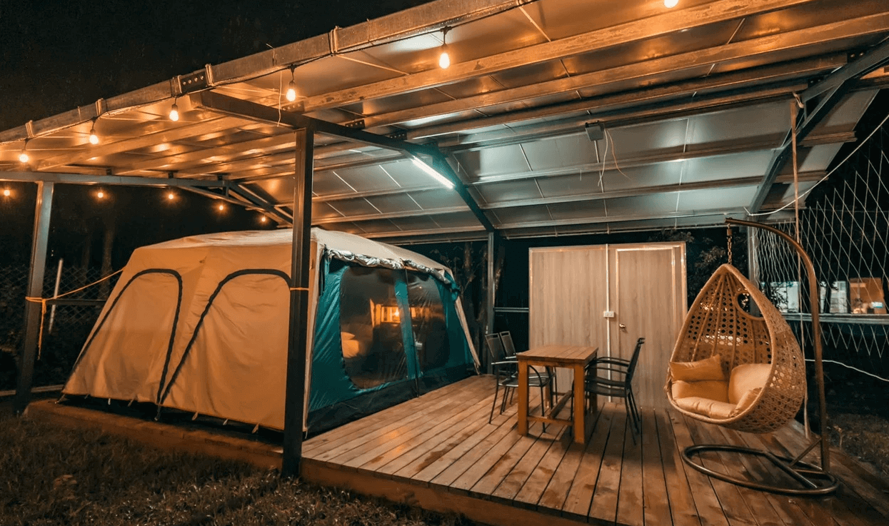 【六龜住宿】高雄六龜【溫德莊園】豪華露營帳篷夜景，帳篷外設有木質露台、吊椅與餐桌，燈串點亮營地，營造溫馨放鬆的氛圍。