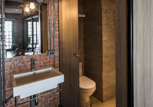 【台南寵物友善住宿】玩聚安平民宿的衛浴空間，以紅磚牆與木質門設計結合現代風格，設有洗手台與獨立廁所區，整體乾淨俐落。