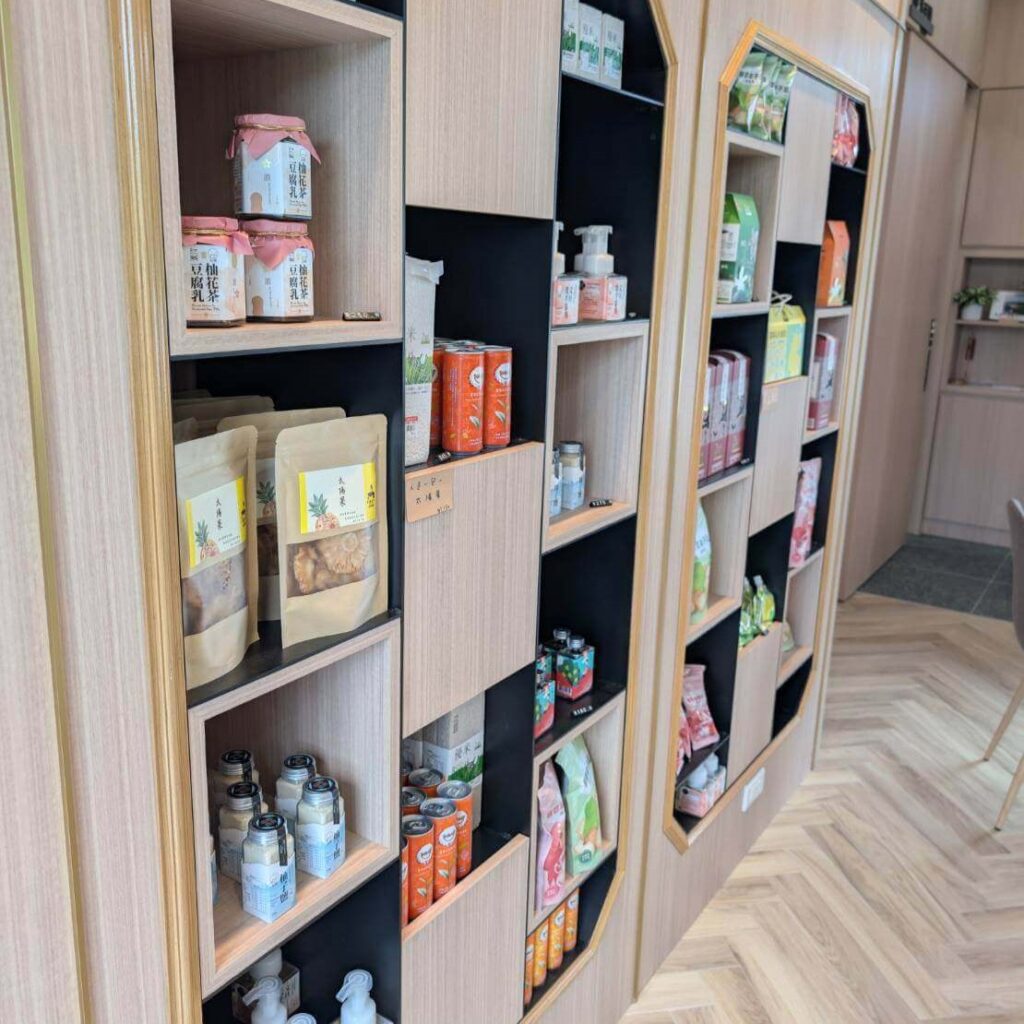【瑞穗美食】「縱谷耘穗咖啡廳」的商品展示牆，整齊陳列多款在地農產品，如豆奶、果乾、茶飲與手工皂等，木質層架設計展現自然風格，空間整潔有序。