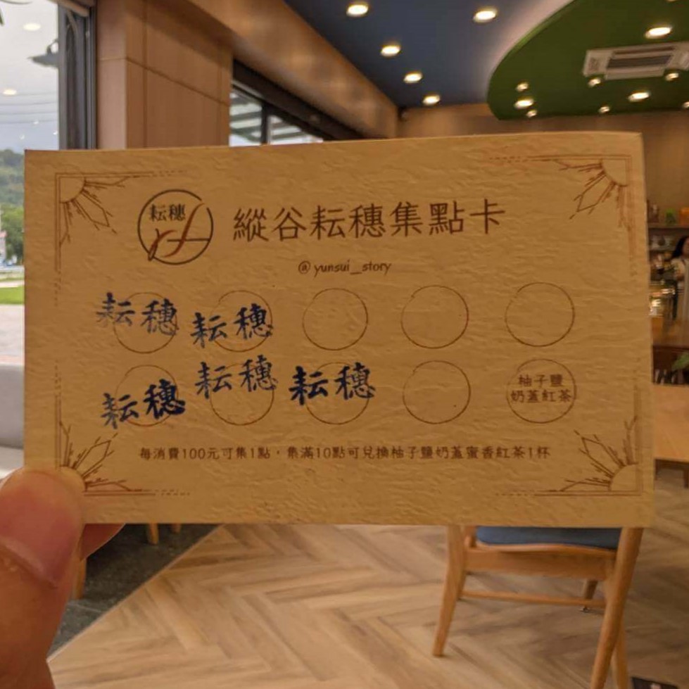 【瑞穗美食】「縱谷耘穗咖啡廳」的集點卡照片，手持卡片拍攝於店內，卡面印有「縱谷耘穗集點卡」字樣，每消費100元可集1點，滿10點可兌換柚子鹽奶蓋紅茶。背景為咖啡廳內部溫暖木質調空間。
