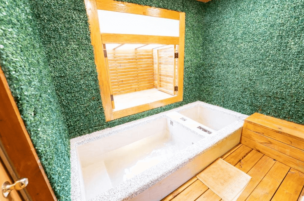 【六龜住宿】高雄六龜【美崙山溫泉渡假山莊】私人湯屋，牆面覆滿綠意植栽裝飾，設有雙人泡湯池與木質座椅，空間明亮乾淨，充滿自然氣息。