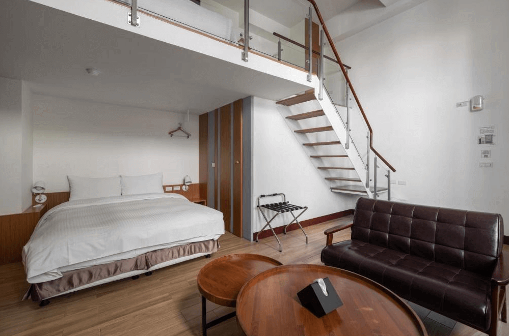 【台南寵物友善住宿】肯辛頓旅店樓中樓客房，結合現代與溫馨風格，設有沙發與木質圓桌，下層臥室搭配上層閣樓床鋪，空間寬敞且採光極佳。