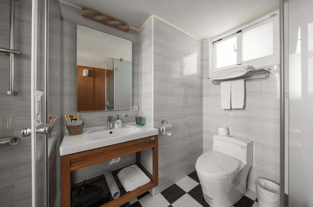 【台南寵物友善住宿】肯辛頓旅店衛浴空間，採灰白色磁磚與木質洗手檯設計，配有乾濕分離淋浴間與大型鏡面，整體乾淨明亮、兼具設計感與實用性。