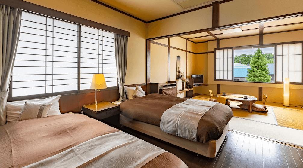 【網走住宿】「能取之莊 Kagari 屋」的雙床房，設有大片拉門窗與柔和燈光，空間寬敞明亮，融合日式榻榻米休憩區與現代化床鋪設計。