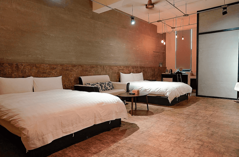 【台南寵物友善住宿】蝸聚民宿四人房，工業風設計融合暖色調燈光，設有兩張大床與小沙發，空間寬敞舒適，適合家庭或朋友入住。