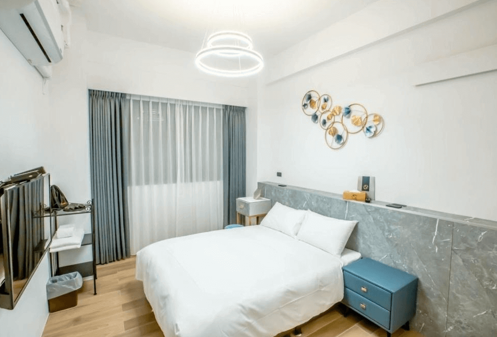 【台南寵物友善住宿】衡定理・畃雨民宿的雙人房，房間以白色與灰藍色調為主，搭配木地板與幾何吊燈，牆面有金屬圓形藝術裝飾，營造現代簡約又柔和的氛圍。