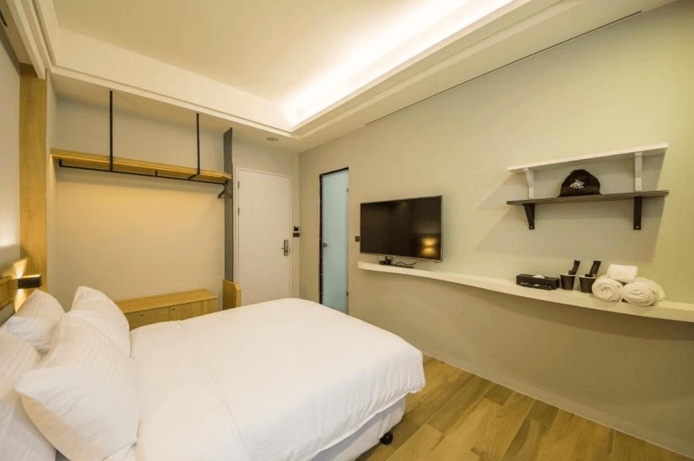 【台南寵物友善住宿】衡定理・畃雨民宿的精緻雙人房，設計簡潔俐落，木質元素與間接照明帶出溫暖感，牆上設有電視與開放式置物架，整體乾淨舒適。