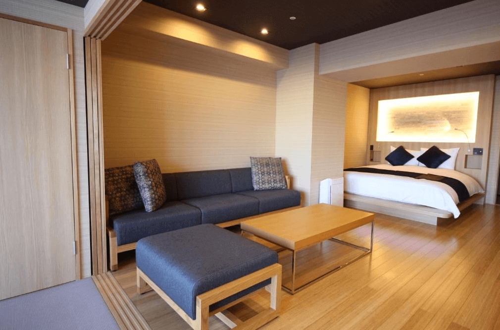 【釧路住宿】釧路世紀城堡飯店套房一景，房內以木質調設計打造溫潤氛圍，設有雙人床與沙發區，展現低調奢華的日式風格。