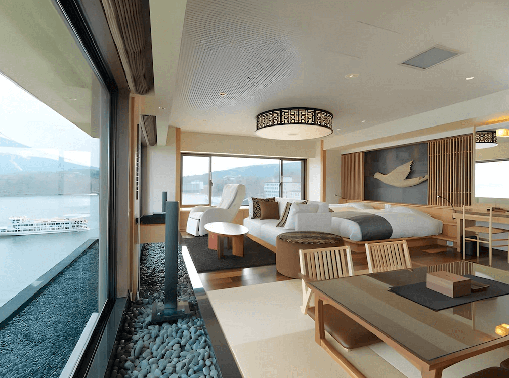 【釧路住宿】阿寒遊久之里鶴雅湖景套房，房內以和風設計融合現代元素，大片窗景可俯瞰阿寒湖，配置雙床與榻榻米座位區，空間明亮優雅。