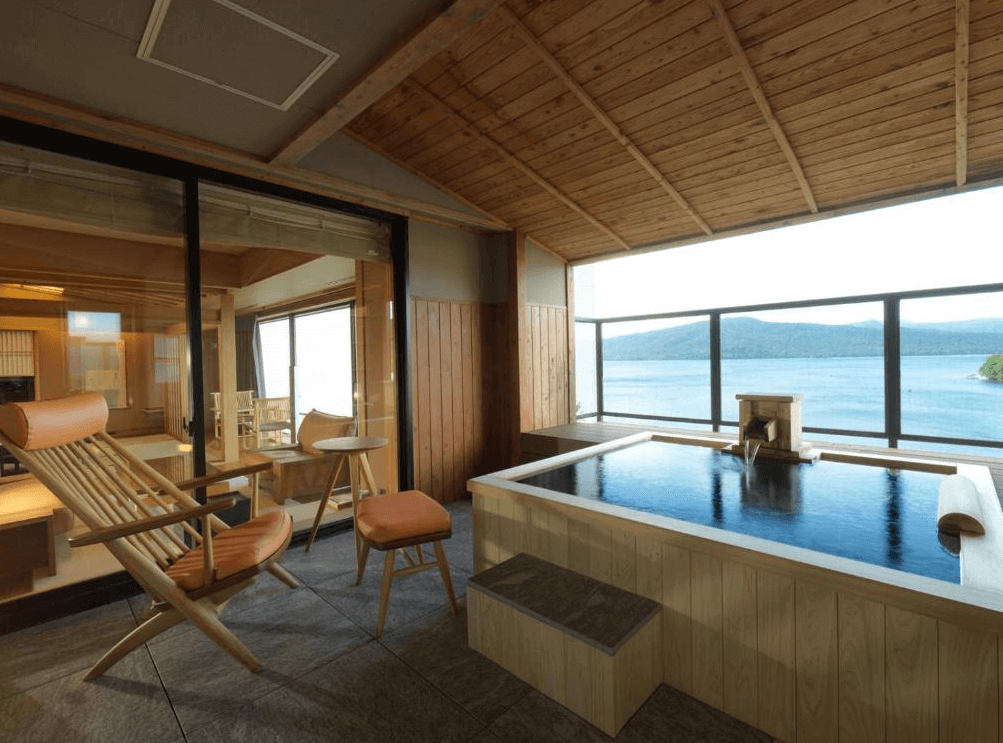 【釧路住宿】阿寒鶴雅別莊鄙之座客房專屬露天風呂，木製浴池面向阿寒湖，搭配休閒座椅與開放式設計，可邊泡湯邊欣賞湖面風光。