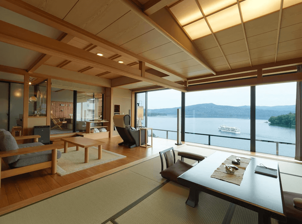 【釧路住宿】阿寒鶴雅別莊鄙之座湖景和室套房，榻榻米地板與木質家具相互融合，窗外可見阿寒湖與遊船景色，充滿日式典雅氣息。