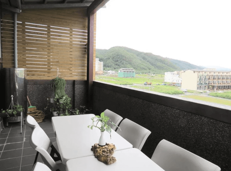 【烏石港住宿】騏驊珍居電梯民宿的戶外景觀陽台,設有白色桌椅組與綠色植栽,可眺望遠方山景與田野風光,是享受早晨陽光與下午茶的放鬆空間。